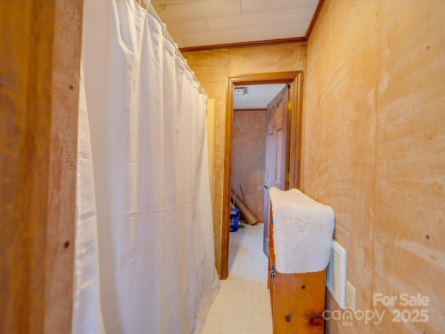 hallway featuring crown molding and wooden walls