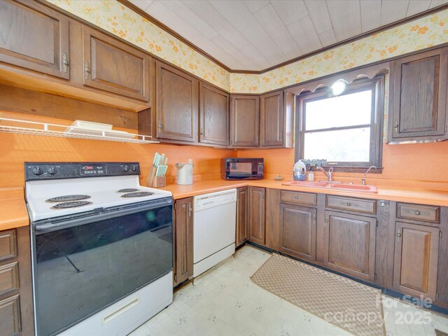 kitchen with white appliances, ornamental molding, and sink