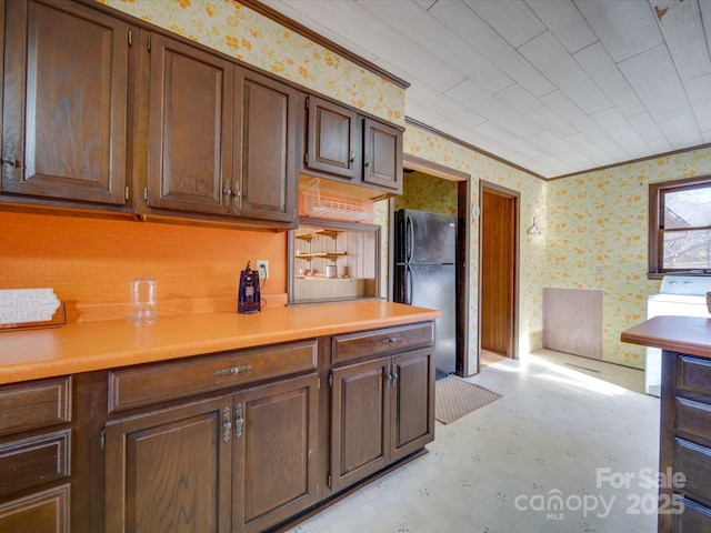 kitchen featuring washer / clothes dryer, crown molding, and black fridge