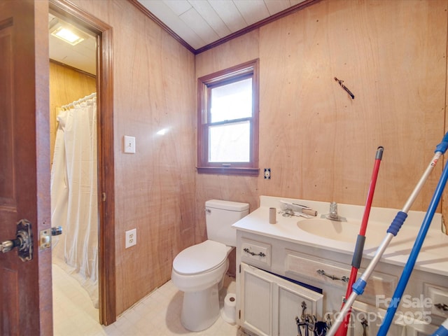 bathroom with ornamental molding, vanity, wooden walls, and toilet