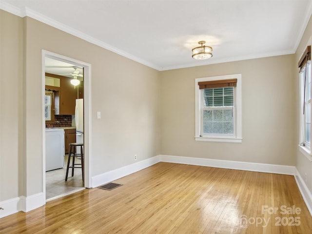 spare room with ornamental molding, a healthy amount of sunlight, and light wood-type flooring