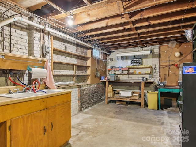 basement with sink, a workshop area, and brick wall