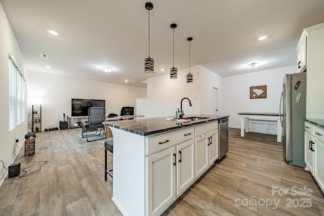 kitchen featuring sink, stainless steel appliances, white cabinets, and a center island with sink