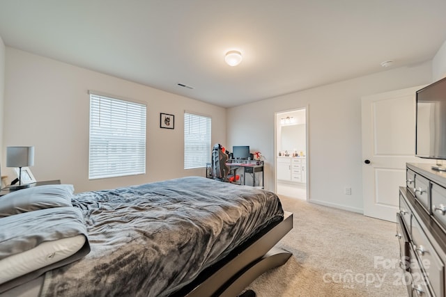 bedroom featuring connected bathroom and light carpet