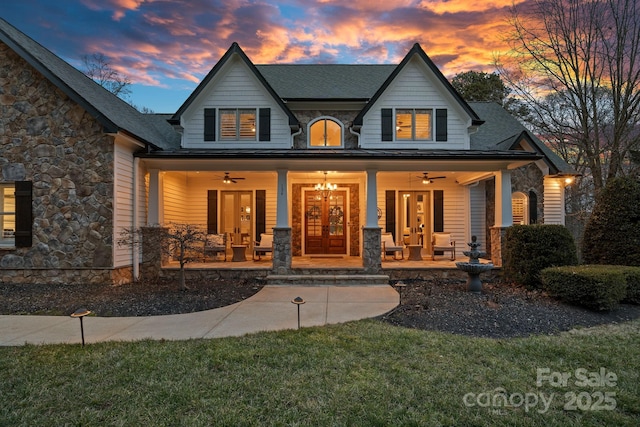 view of front facade featuring covered porch, stone siding, and french doors