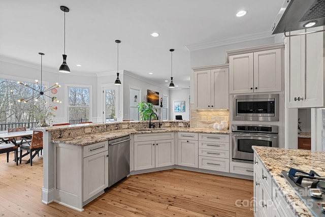 kitchen with stainless steel appliances, tasteful backsplash, ornamental molding, a sink, and a peninsula