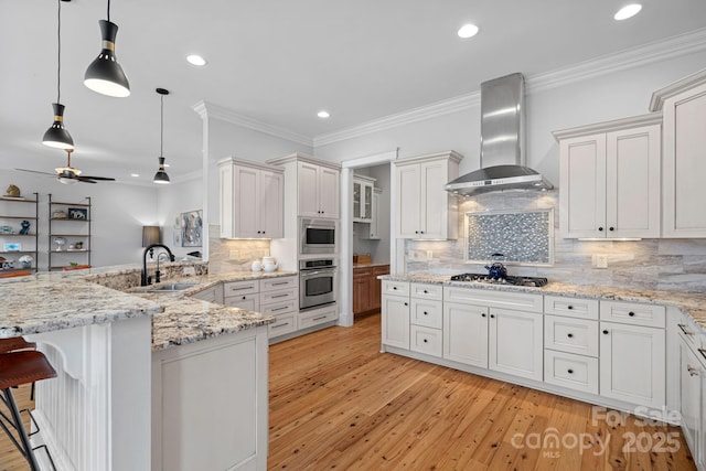 kitchen with crown molding, stainless steel appliances, a sink, wall chimney range hood, and a peninsula