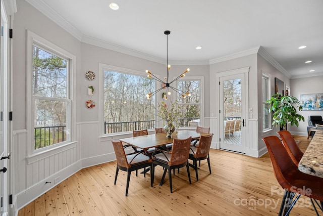 dining area with light wood-type flooring, a healthy amount of sunlight, and crown molding