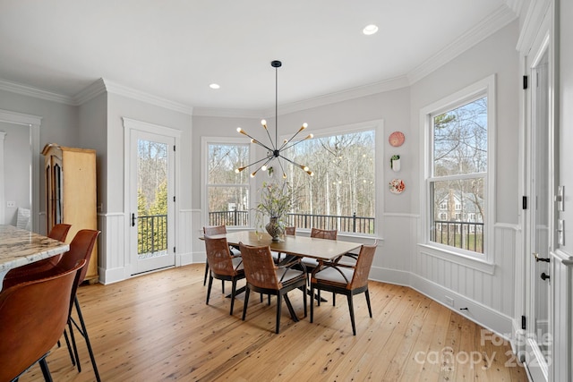 dining area featuring light wood finished floors, ornamental molding, a wealth of natural light, and a wainscoted wall