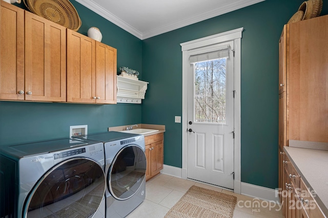 washroom with cabinet space, baseboards, washing machine and clothes dryer, crown molding, and a sink