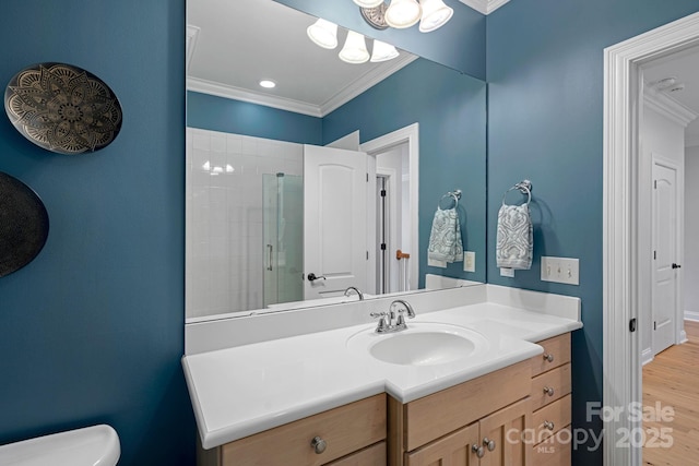 full bath featuring toilet, ornamental molding, a tile shower, vanity, and wood finished floors