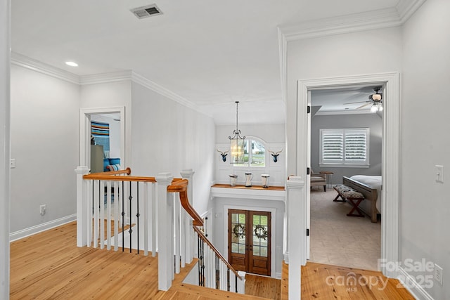 interior space featuring visible vents, light wood finished floors, an upstairs landing, and crown molding