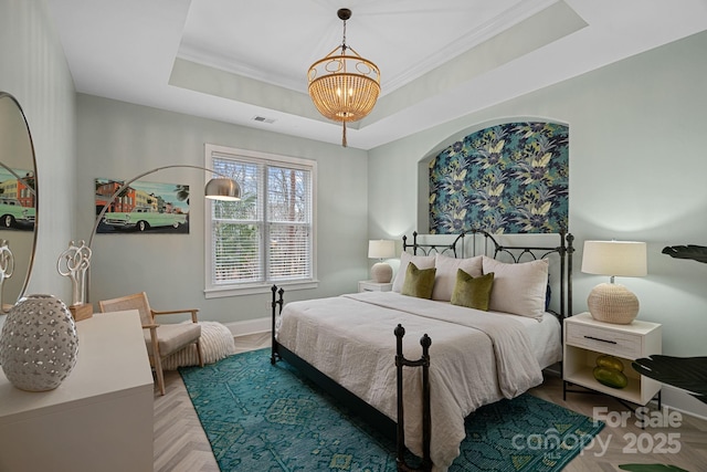 bedroom with visible vents, baseboards, a tray ceiling, an inviting chandelier, and crown molding