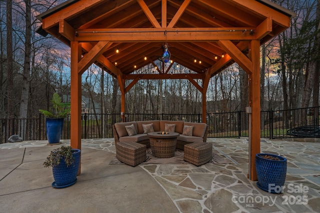 patio terrace at dusk featuring a gazebo, fence, and an outdoor living space with a fire pit