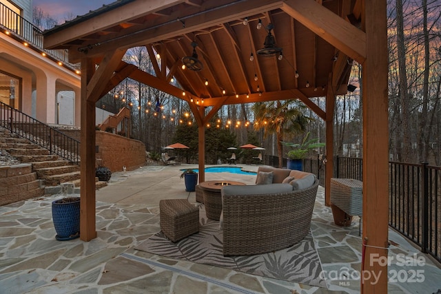 patio terrace at dusk featuring stairs, fence, a fenced in pool, and a gazebo