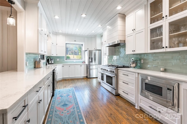 kitchen featuring premium range hood, decorative light fixtures, white cabinets, stainless steel appliances, and light stone countertops