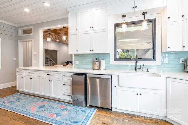 kitchen with sink, hardwood / wood-style flooring, white cabinetry, decorative light fixtures, and stainless steel dishwasher