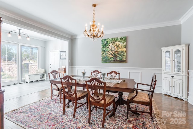 dining area with an inviting chandelier, hardwood / wood-style floors, and ornamental molding