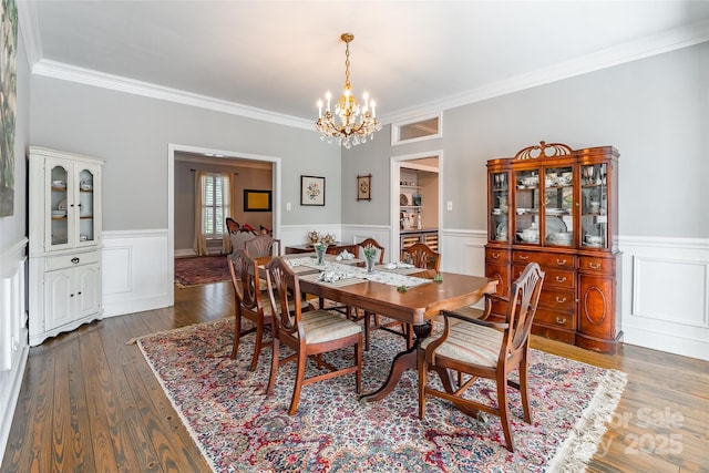 dining room with crown molding, dark wood-type flooring, and an inviting chandelier