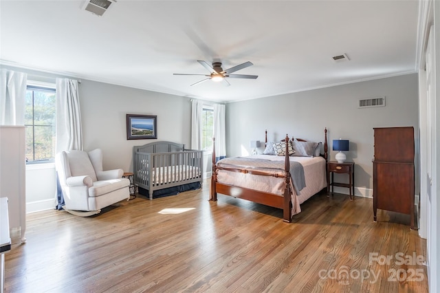 bedroom with hardwood / wood-style flooring, ceiling fan, ornamental molding, and multiple windows