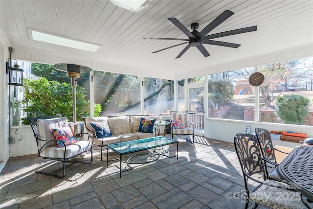 sunroom / solarium with a skylight, plenty of natural light, wooden ceiling, and ceiling fan