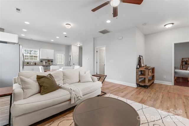 living area featuring baseboards, light wood-type flooring, visible vents, and recessed lighting