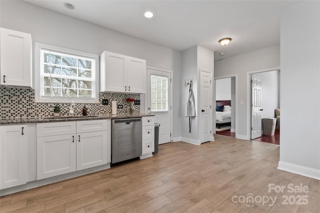 kitchen with a sink, white cabinetry, dark stone counters, and dishwasher