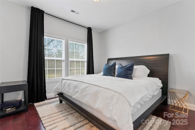 bedroom with baseboards, visible vents, and dark wood-type flooring