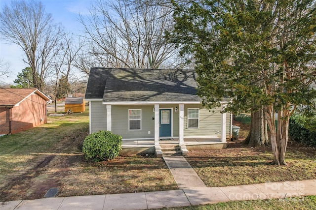 bungalow-style house featuring roof with shingles and a front lawn