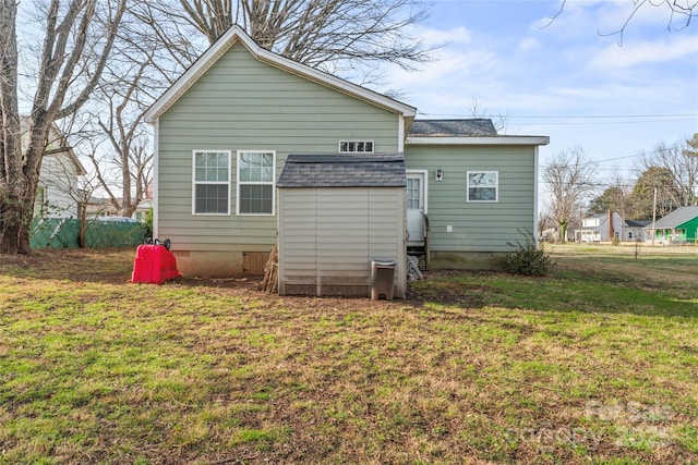 back of property featuring crawl space, a storage unit, a lawn, and roof with shingles