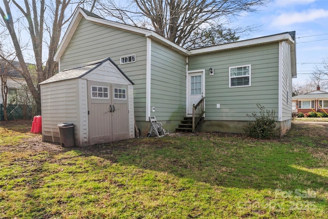 rear view of property with entry steps, an outdoor structure, and a yard