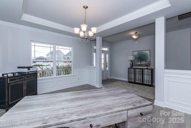 unfurnished dining area featuring crown molding, a tray ceiling, hardwood / wood-style flooring, and a notable chandelier