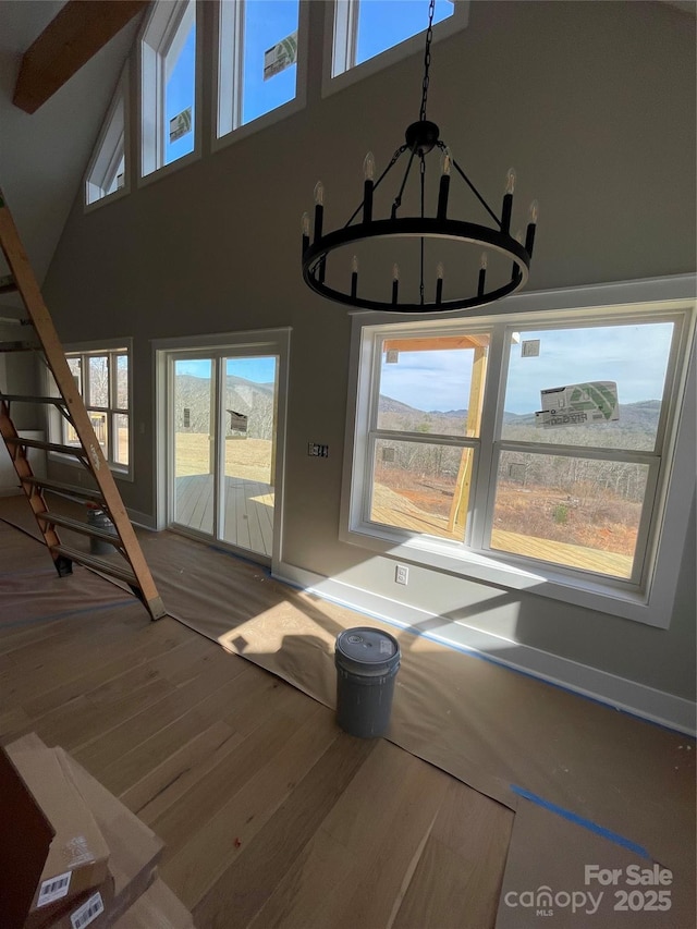 interior space featuring a chandelier, a healthy amount of sunlight, a high ceiling, and wood finished floors