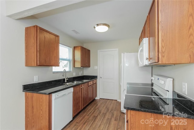 kitchen featuring sink, dark stone countertops, white appliances, and light hardwood / wood-style flooring