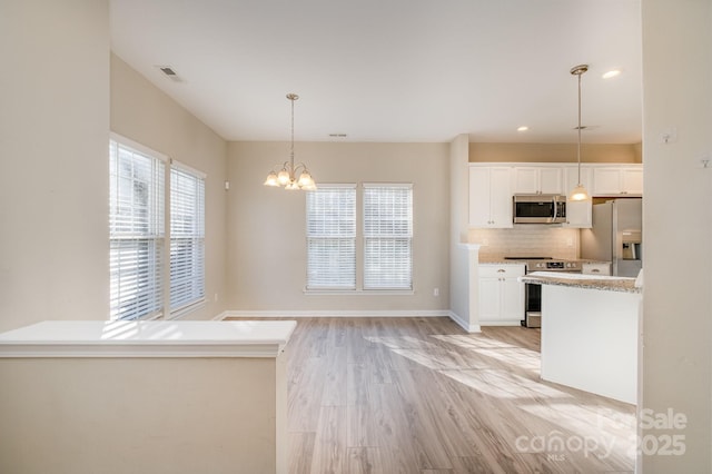 kitchen with tasteful backsplash, stainless steel appliances, decorative light fixtures, and white cabinets