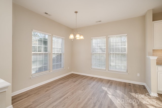 unfurnished dining area with a notable chandelier and light hardwood / wood-style flooring