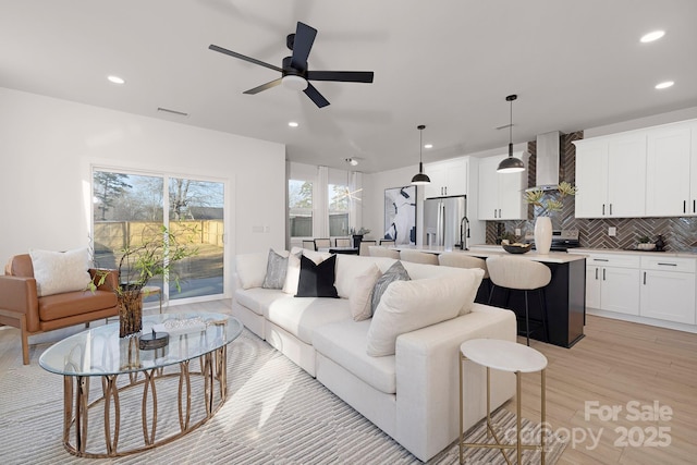 living room with ceiling fan, sink, and light hardwood / wood-style floors