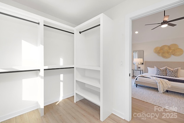 walk in closet featuring a barn door, hardwood / wood-style floors, and ceiling fan