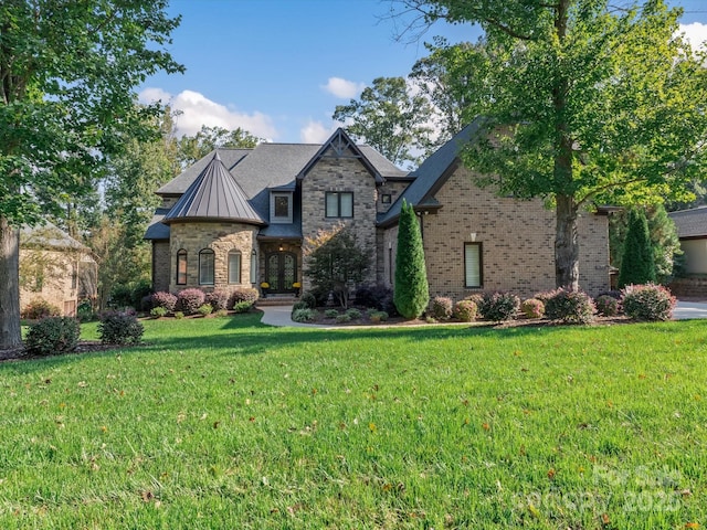 view of front facade with a front yard, a standing seam roof, brick siding, and metal roof