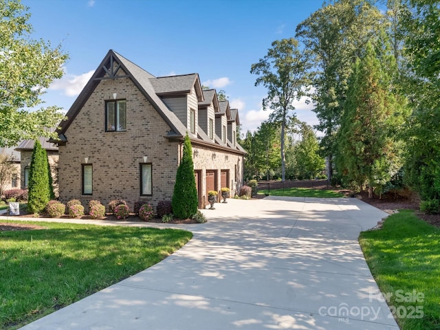 view of side of property with driveway, a garage, a lawn, and brick siding