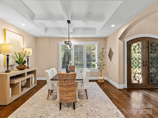 dining area with dark hardwood / wood-style floors, ornamental molding, coffered ceiling, beam ceiling, and french doors