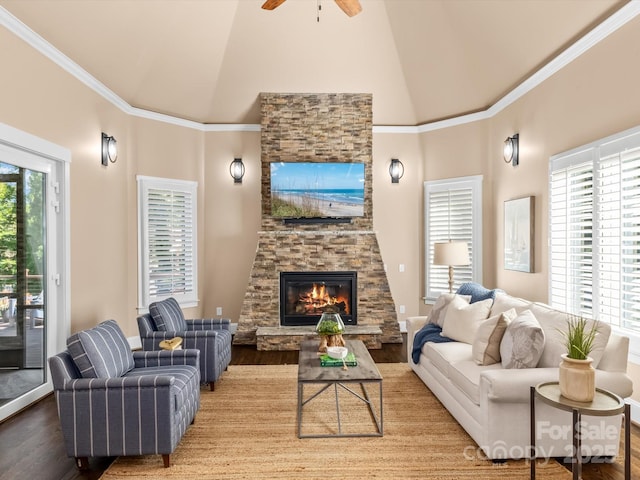 living area featuring ceiling fan, ornamental molding, wood finished floors, a fireplace, and high vaulted ceiling