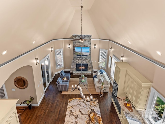 living room featuring dark hardwood / wood-style floors, ceiling fan, a fireplace, and high vaulted ceiling