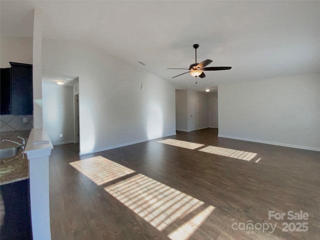 unfurnished living room featuring sink, vaulted ceiling, dark hardwood / wood-style floors, and ceiling fan