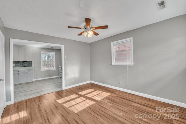 spare room featuring ceiling fan, a textured ceiling, and light wood-type flooring