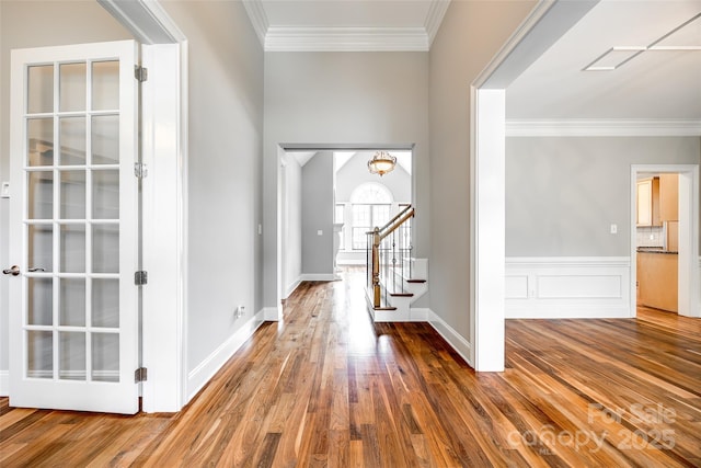 entrance foyer featuring a wainscoted wall, crown molding, stairway, and wood finished floors