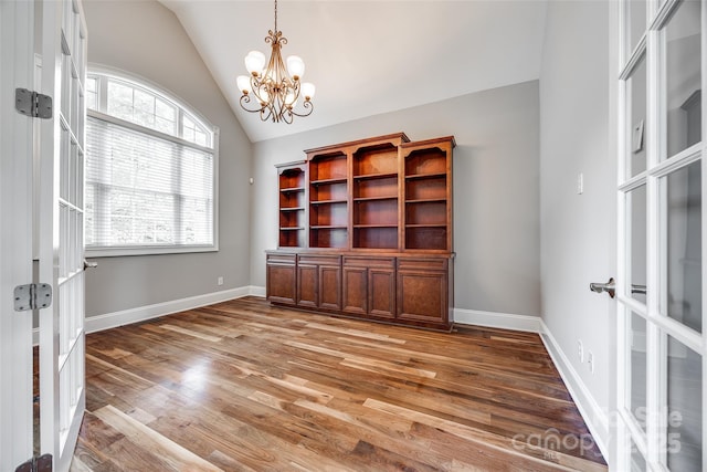 interior space with lofted ceiling, baseboards, a notable chandelier, and light wood finished floors