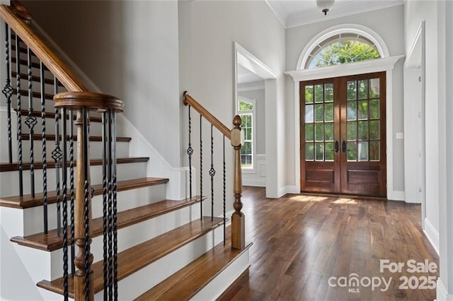 foyer entrance featuring baseboards, stairway, wood finished floors, crown molding, and french doors