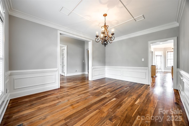 unfurnished room with ornamental molding, dark wood finished floors, and a notable chandelier