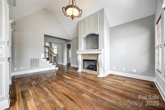 unfurnished living room featuring stairway, dark wood-style floors, visible vents, and a tile fireplace